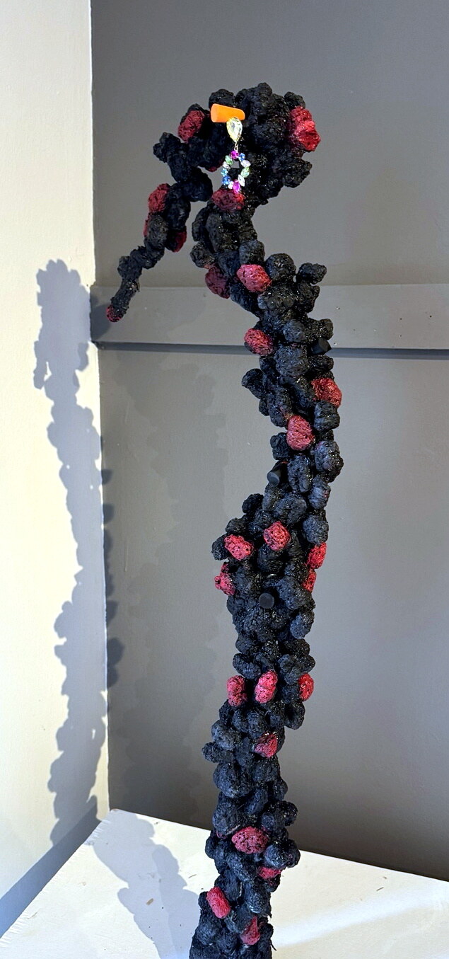 Woman 2, a tall organic female sculpture with dark textured wounds and colored details